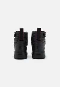 Botas de tobillo acolchadas negras con un acabado brillante, que presentan un logo audaz en la parte trasera y acentos rojos en el talón y la lengüeta.