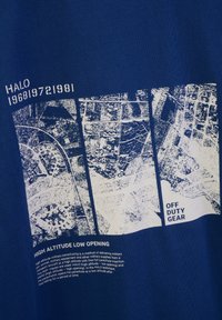 Blå tygtröja med en vit grafik av flygkartor och text. Detaljer inkluderar "HÖG ALTITUDE LÅG ÖPPNINGS" och "OFF DUTY GEAR."