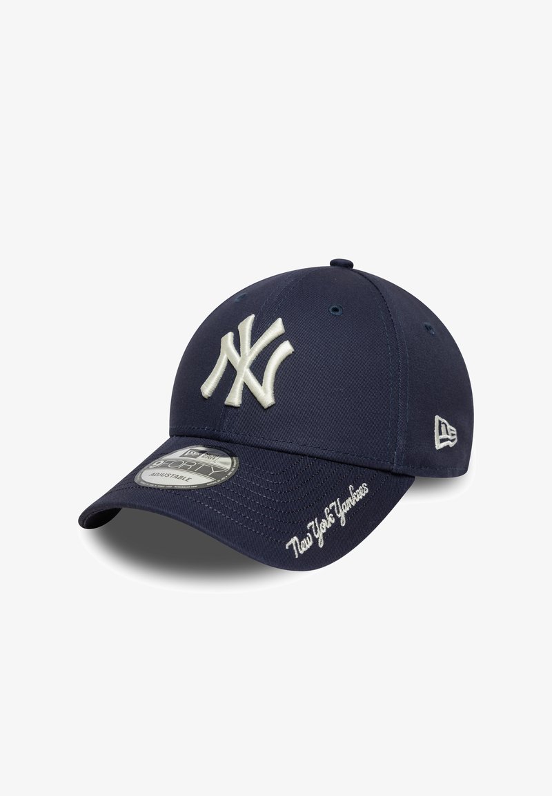 Blå baseballkasket lavet af stof, med hvidt broderet New York Yankees-logo foran og tekst langs skyggen. Struktureret design.