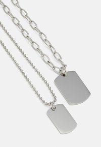 Two silver dog tag necklaces. One features a smooth, rectangular pendant on a ball chain, and the other has a larger pendant on a linked chain.