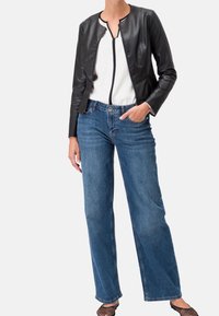 Veste en simili cuir noir avec un col rond et une fermeture éclair, associée à un jean bleu clair à jambes larges, présentant des poches avant et une coupe décontractée.