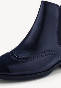 Mörkblå läder chelsea boot med en polerad yta, präglade detaljer och dekorativa perforeringar längs framsidan. Slät textur.