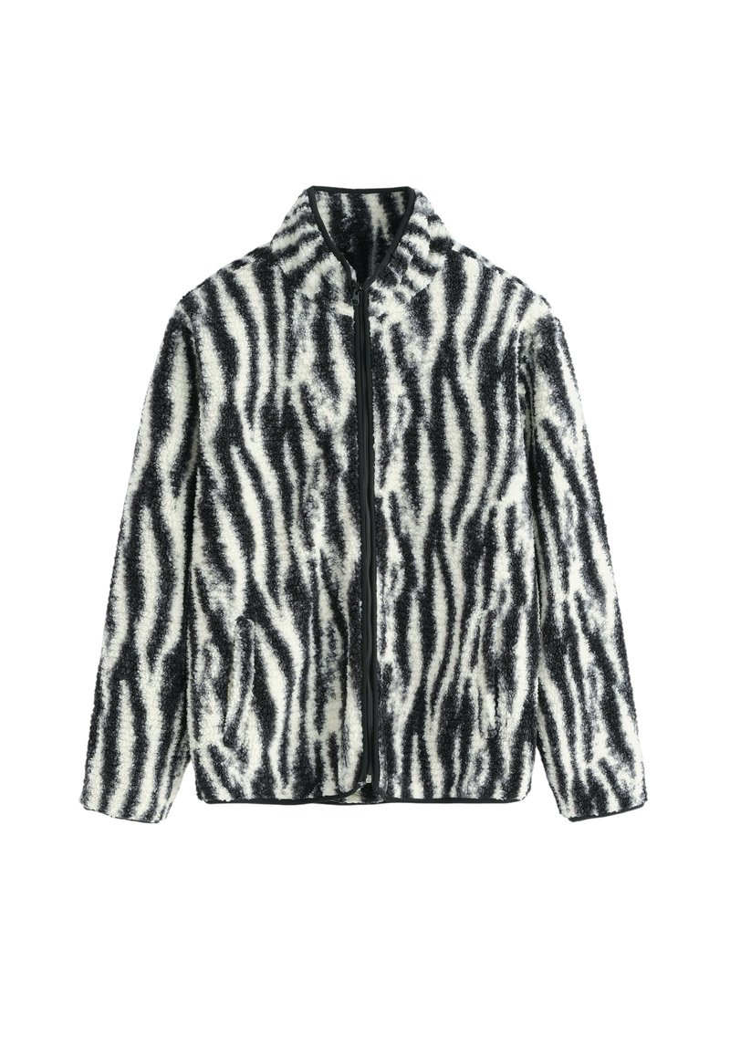 Veste en fausse fourrure avec un motif de rayures zèbre noir et blanc, dotée d'une fermeture éclair sur le devant et d'un col montant, fabriquée à partir d'un matériau doux et texturé.