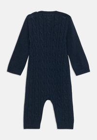 Μπλε ναυτικό πλεκτό ολόσωμο με σχέδιο καλωδίου, μακριά μανίκια και κουμπώματα στους ώμους για εύκολη ντύσιμο.