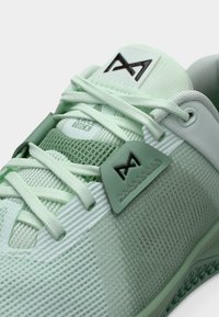 Chaussure de sport vert menthe avec dessus en mesh, accents texturés, lacets plats et écusson logo. Dispose d'une semelle en caoutchouc lisse et d'un design léger.