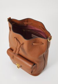 Borsa a secchiello in pelle marrone con finitura testurizzata, chiusura a cordoncino e tasca frontale con chiusura dorata. Interno foderato in bordeaux.