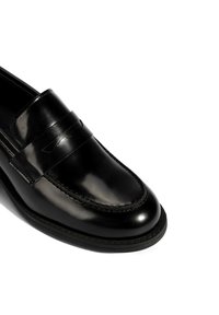 Zwarte lederen loafer met een gladde afwerking, gekenmerkt door een gestikte naad en een decoratieve band over de voorkant. Rubberen zool. Tijdloos ontwerp.