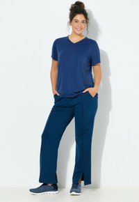 Granatowy sportowy strój składający się z krótkiego topu z dekoltem w serek z kwiatowym wzorem oraz dopasowanych spodni z rozcięciami po bokach i lamówkami.