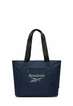 Granatowa torba typu tote Reebok z czarnymi uchwytami, przednią kieszenią na zamek oraz logo Reebok w kolorze szarym nadrukowanym z przodu.
