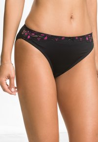 Slip bikini neri con bordo in pizzo floreale rosa e nero, con un bordo ondulato e un piccolo fiocco decorativo sul davanti.