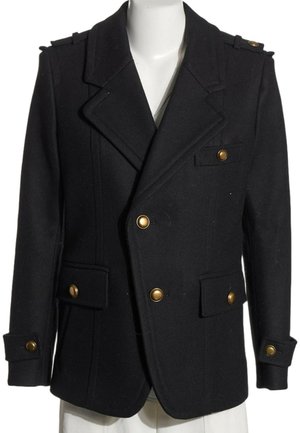 Abrigo pea coat negro de doble botonadura con botones dorados, cuello con muesca, hombreras y bolsillos con solapa en un torso de maniquí blanco.
