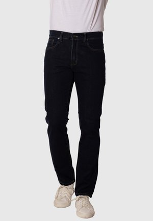 Jeans de denim azul oscuro con corte ajustado, que cuentan con cinco bolsillos, costuras en amarillo contraste y un cierre clásico de botón y cremallera.