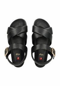 Schwarze Leder-Sandalen mit überkreuzten Riemen, einer goldenen Schnalle, strukturiertem Oberflächen und flacher Sohle. Auffällige goldene und rote Akzente auf der Innensohle.