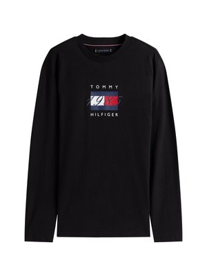 Juodas ilgo rankovės medvilninis marškinėlis, turintis centrinį grafikos dizainą raudonos, baltos ir mėlynos spalvų deriniu, kuriame parašyta "TOMMY 1985 HILFIGER."