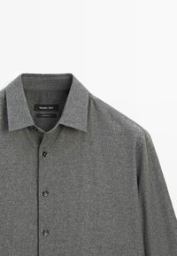 Camicia grigia con bottoni, realizzata in un tessuto a maglia testurizzato, colletto alla francese e bottoni neri. Etichetta con scritto "Massimo Dutti."