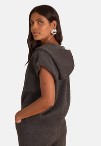 Dark gray knit hoodie top featuring short sleeves, a spacious hood, and a relaxed fit. Smooth texture, with a front pocket detail.