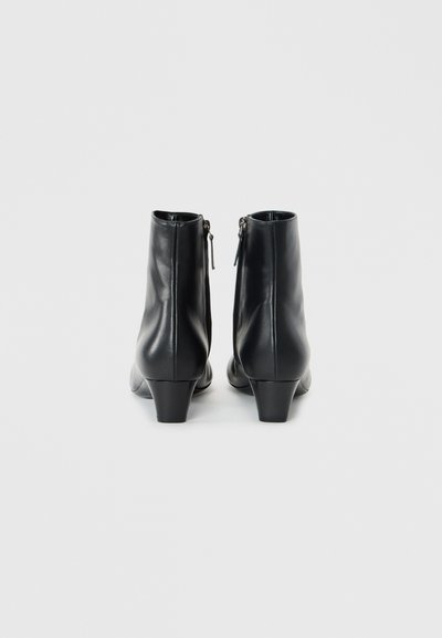Bottines en cuir noir avec une texture lisse, un talon effilé et des zips à l'arrière pour un enfilage facile. Design simple et épuré.