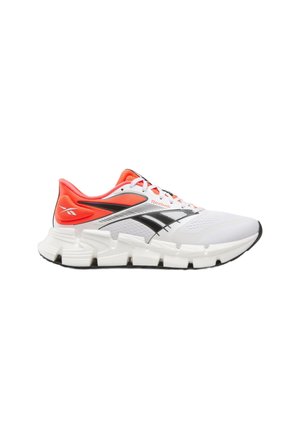 Weiß-orangefarbener Reebok Laufschuh mit schwarzem Logo, dicker segmentierter Sohle und weißen Schnürsenkeln, gezeigt im rechten Seitenprofil vor weißem Hintergrund.