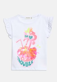 Λευκό πουκάμισο με βολάν στα μανίκια, με ροζ φλαμίνγκο που λάμπει, φορά γυαλιά ηλίου σε σχήμα καρδιάς και κείμενο "Η Βασίλισσα της Φασαρίας" στο μπροστινό μέρος.