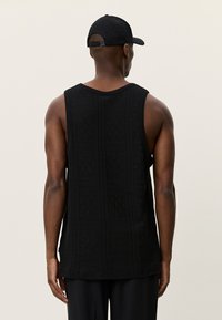 Μαύρο αμάνικο τοπ με υφασμένο μοτίβο, στρογγυλή λαιμόκοψη και άνετη εφαρμογή. Η πίσω όψη αναδεικνύει λεπτομέρειες και καθαρό τελείωμα.