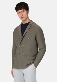 Doppelreihige Jacke aus geripptem grauem Stoff mit Knopfverschluss und zwei Vordertaschen. Schlanke Passform mit spitzem Kragen.