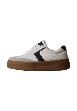 Baskets blanches avec accents noirs, lacets blancs et semelle épaisse en caoutchouc marron, vues de profil sur un fond uni.