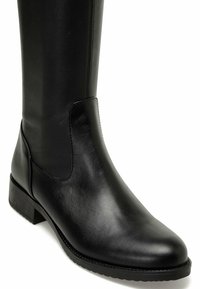 Bota de cuero negro hasta la rodilla con un acabado liso, punta redondeada, paneles laterales elásticos y un tacón bajo en bloque. Detalle de costura sencilla en los laterales.