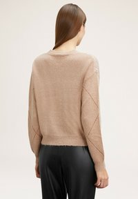 Hellbeige gestrickter Pullover mit einem cropped Schnitt, strukturiertem Finish und Rautenmuster an den Ärmeln. Rundhalsausschnitt und gerippter Saum.