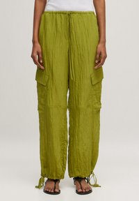 Groene, gekreukte stoffen broek met elastische taille en verstelbare strikjes, voorzien van twee zijcargo zakken enGathered cuffs bij de enkels.