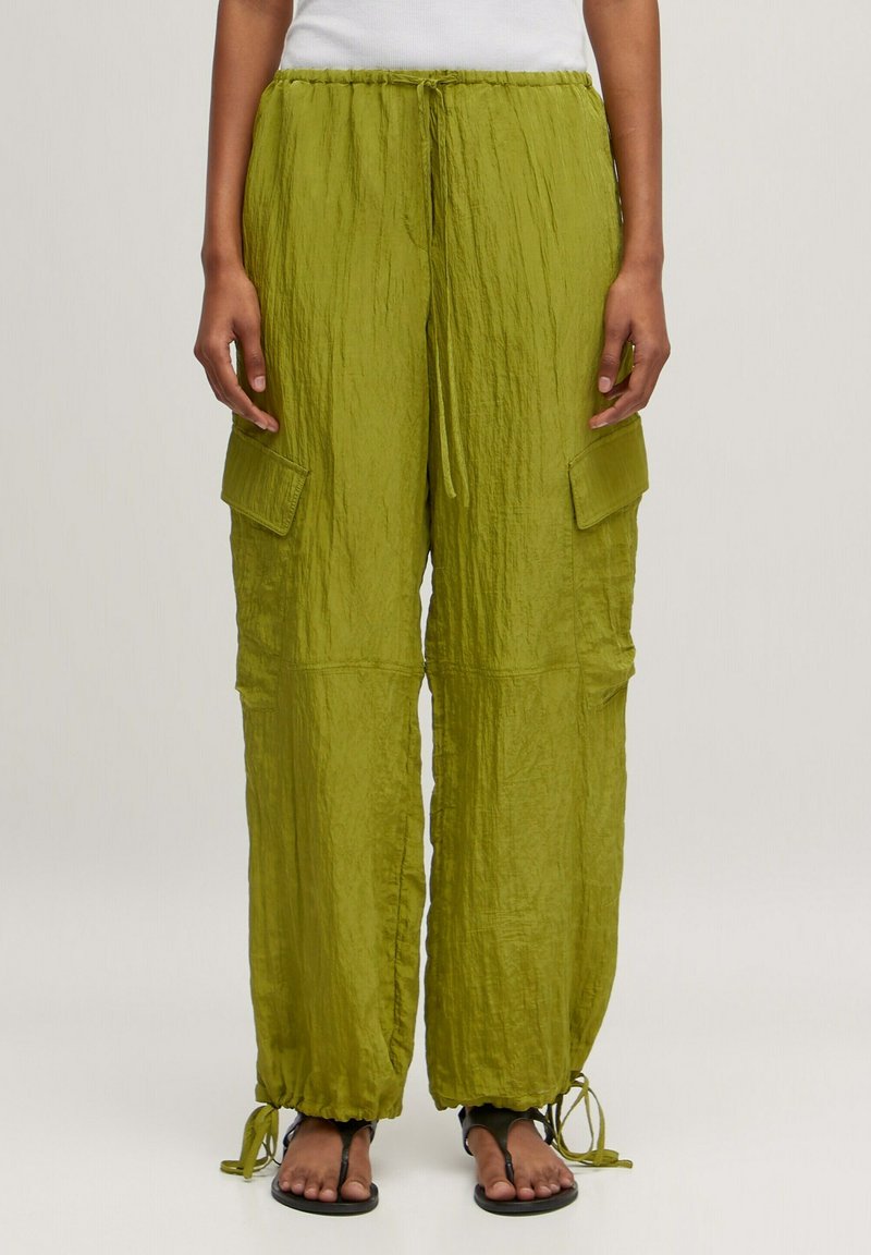 Groene, gekreukte stoffen broek met elastische taille en verstelbare strikjes, voorzien van twee zijcargo zakken enGathered cuffs bij de enkels.