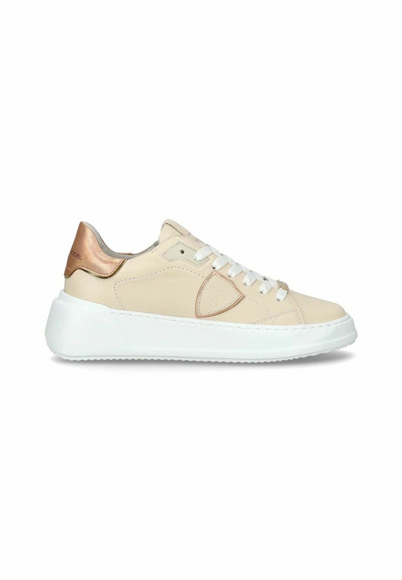 Beige lædersneakers med en hvid sål, der har en rosaguld detalje på hælen og hvide snørebånd. Minimalistisk design med diskret syning.