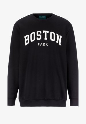Felpa nera con la scritta "BOSTON PARK" stampata in bianco, abbinata a jeans neri sbiaditi e scarpe da ginnastica nere con suola bianca.