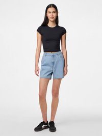 Černý proužkovaný crop top s krátkým rukávem, spárovaný s světle modrými denimovými šortkami s vysokým pasem a černými teniskami s bílými akcenty.