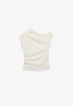 Haut sans manches couleur blanc cassé avec encolure bateau, fronces latérales discrètes sur la droite, et bordure en dentelle festonnée à l'ourlet.