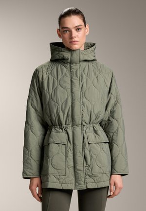 Gequilted groene jas met een capuchon, elastische taille, twee vo pockets en een gestructureerd patroon. Heeft een lichtgewicht materiaal en een ontspannen pasvorm.