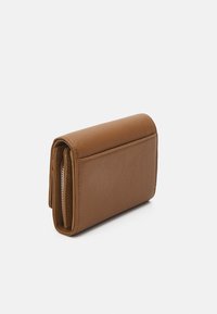 Portefeuille en cuir marron avec une surface texturée, de forme rectangulaire et un compartiment zippé ; légèrement plié pour une vue compacte.