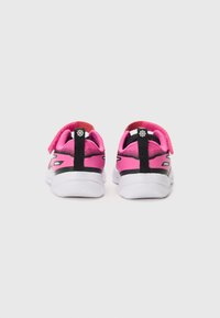 Chaussures de sport pour enfants avec une tige en maille rose, des accents noirs et des semelles blanches. Elles sont dotées d'une sangle en velcro et d'un talon rembourré pour le confort.