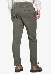 Pantaloni verde oliva in tessuto strutturato, slim fit, con tasche laterali e due tasche posteriori con chiusura a bottoni. Orlo con risvolto.