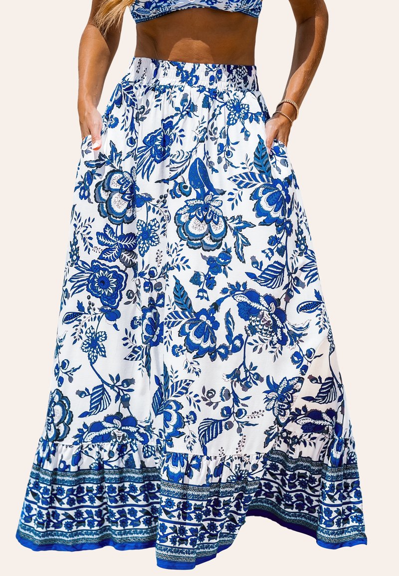 Longue jupe en tissu blanc avec un motif floral bleu. Dotée d'une taille élastique et de poches latérales. Détail de bord ruffle.