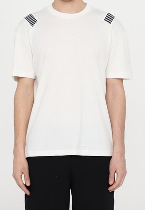 Weißes T-Shirt mit kurzen Ärmeln, schwarzen gestreiften Akzenten auf den Schultern und kleinem EA7-Logo auf der Brust. Glatte Textur, reguläre Passform.