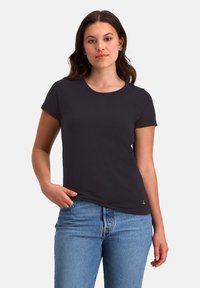 Zwarte t-shirt met korte mouwen en een ronde halslijn, gemaakt van zachte stof. Draagt in een lichte spijkerbroek, met een klein logo-detail.