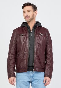 Bordeauxrote Lederjacke mit Reißverschluss, zwei Brusttaschen und einem grauen Kapuzenpullover darunter. Glatte Textur, normale Passform und lange Ärmel.