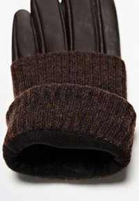 Bruine leren handschoenen met geribbelde wollen manchetten. De manchetten vertonen een gestructureerd patroon, contrasterend met het gladde leer.