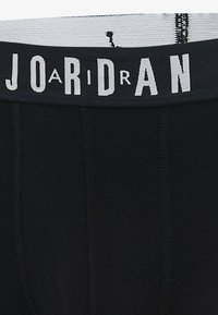 Black boxer shorts featuring a gray elastic waistband with "JORDAN" lettering. The fabric appears smooth and stretchy, suitable for comfort.