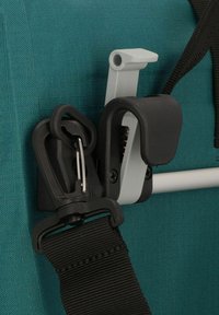 Fibbia in plastica nera con un gancio metallico argentato che fissa una cinghia nera su uno sfondo di tessuto teal, mettendo in evidenza un design robusto e pratico.