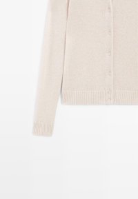 Cardigan beige in maglia con bottoni davanti, maniche lunghe e polsini e orlo a coste, mostrato su sfondo bianco.