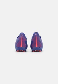 Scarpe da calcio con una tomaia in rete viola con accenti rosa, finitura texturizzata e tacchetti conici per una maggiore aderenza. Doppie linguette di tiraggio sul tallone.