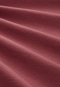 Měkká, texturovaná látka v hluboké růžové barvě, s hladkými, vlnícími se vlnami a matným povrchem. Vhodná pro různé textilní aplikace.