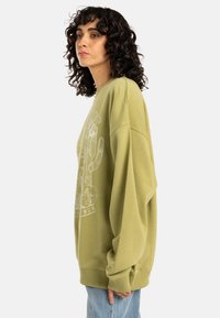 Olijfgroen oversized sweatshirt met een ronde hals, verlaagde schouders en cactus grafische print. Zachte stof met geribde cuffs.