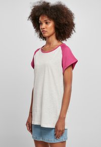 Grå og rosa T-skjorte med korte ermer, rund hals og en avslappet passform. Mykt stoff med en kontrastdesign på ermene.